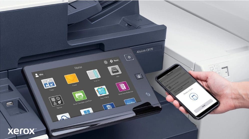 Xerox® ConnectKey®: Mobiles Drucken und Scannen Eine Nahaufnahme der Hand einer Person, die ein Smartphone hält, das drahtlos mit dem Touchscreen-Bedienfeld eines Xerox-Multifunktionsdruckers verbunden ist und die nahtlosen mobilen Druck- und Scanfunktionen von Xerox ConnectKey demonstriert.